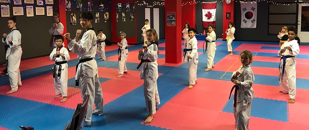 A diverse group of young students practicing stances in a professional karate for kids studio to improve youth fitness.