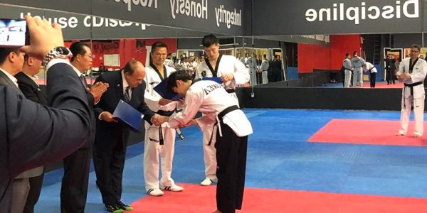 A student receiving an official martial arts certification from a master during a formal belt promotion ceremony.